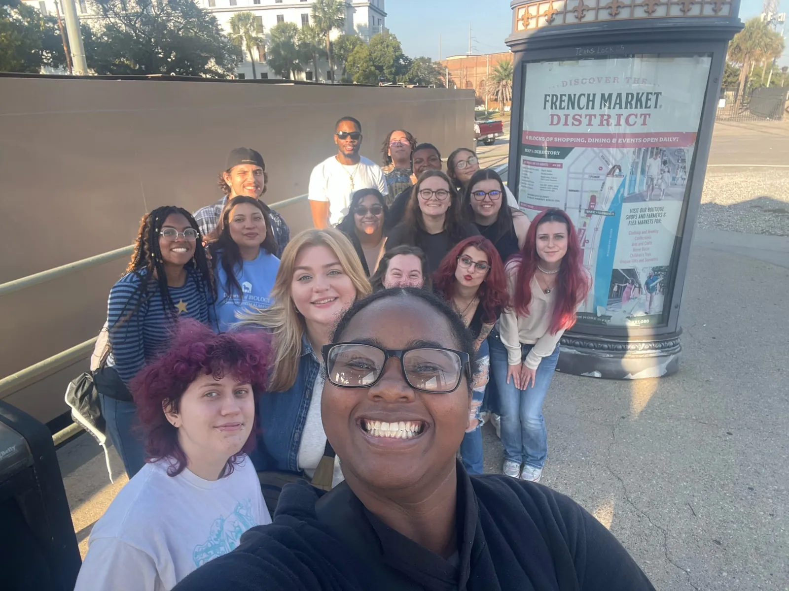 Candid selfie-style group photo by a sign